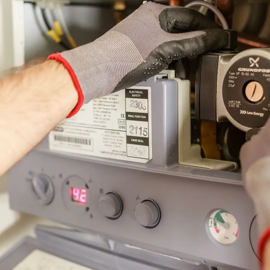 Heating engineer working at an open wall mounted combi boiler