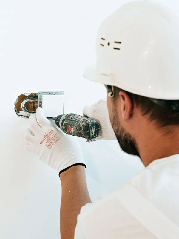 Electrician in a hard hat fitting a wall switch